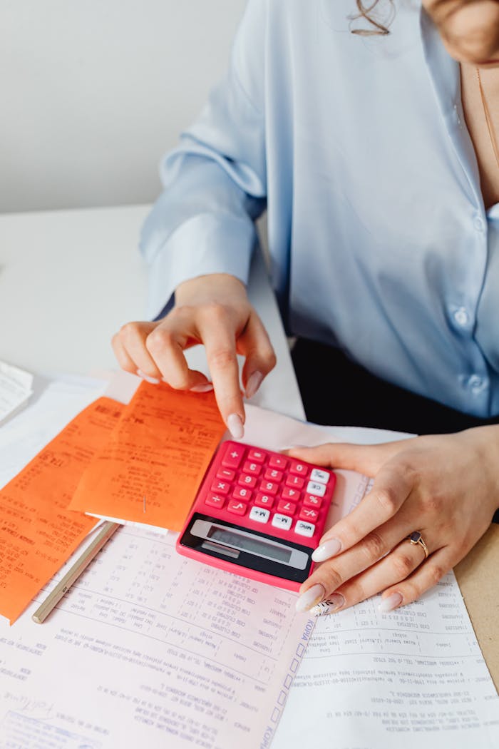 our-mission Person calculating finances with pink calculator and receipts, close-up view.