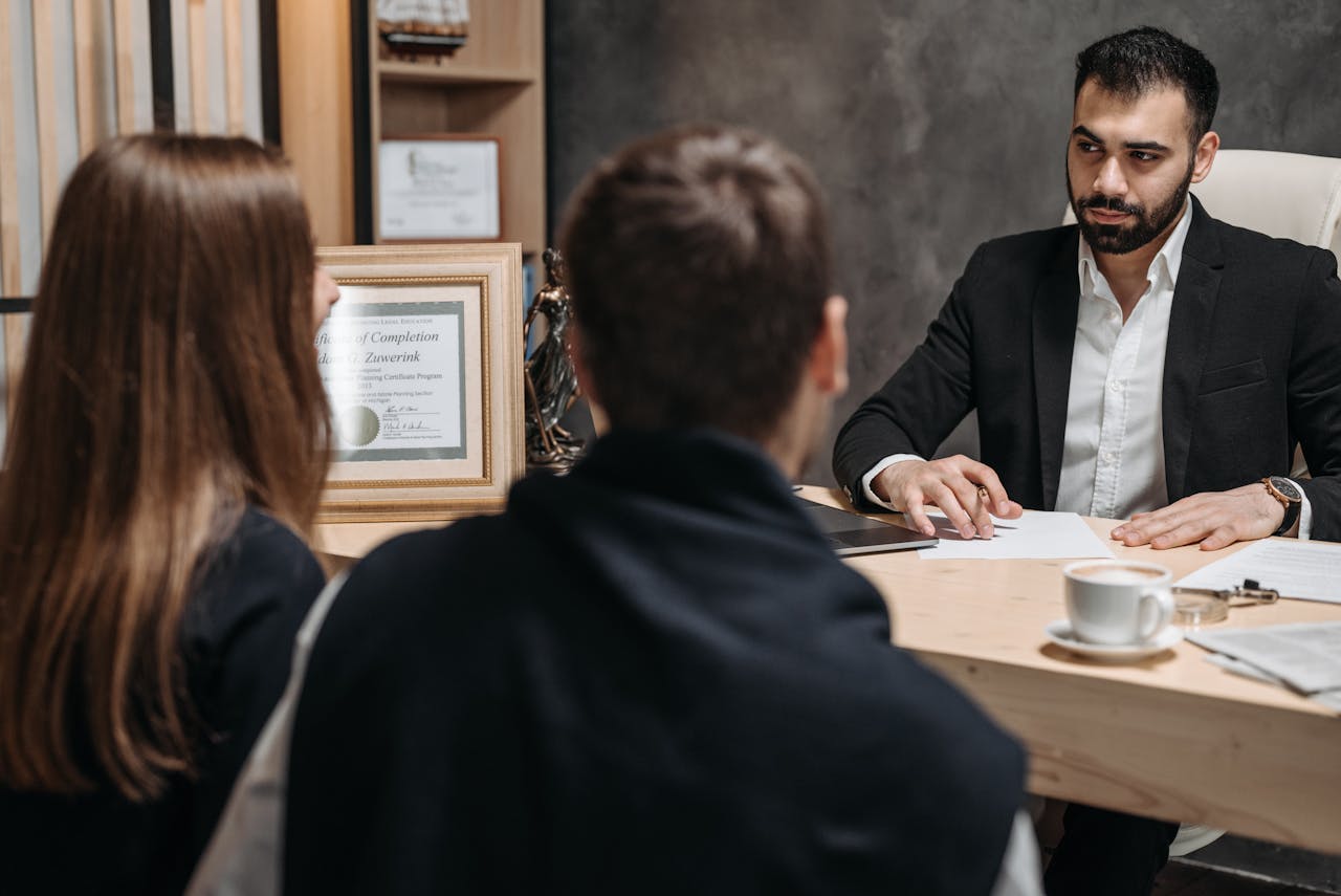 why-choose-us A lawyer in an elegant office meeting with clients, discussing documents.