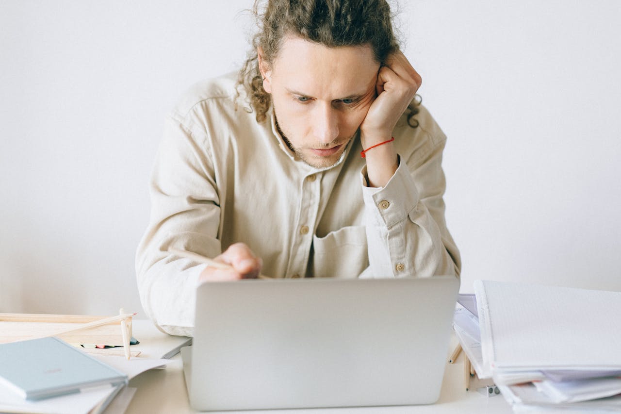 portfolio-05 Adult man stressed at work, experiencing burnout while working on laptop at desk.
