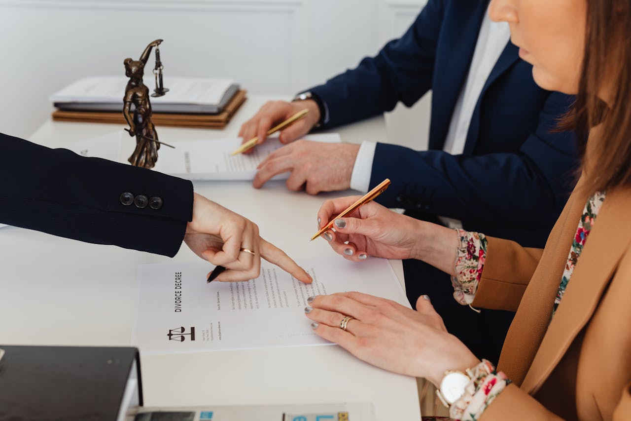 stats-img Hands signing a divorce decree, with a justice statue nearby, symbolizing legal proceedings.